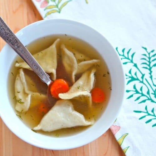A bowl of chicken soup with dumplings and carrots
