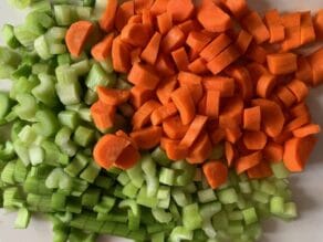 Celery and carrots chopped and piled on a cutting board.