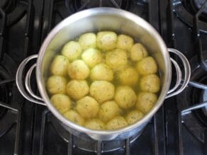 Fluffy, light matzo balls floating at the top of a pot on stovetop.