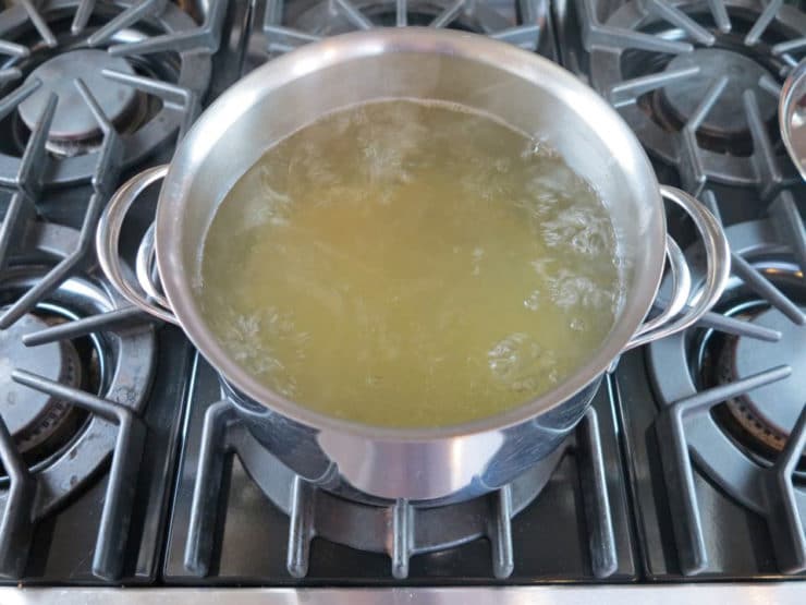 Boiling chicken broth in a soup pot on the stovetop.