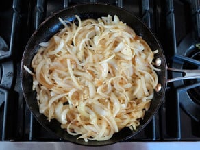 Sauteing sliced onions in a skillet.