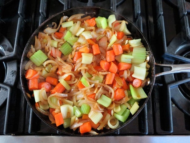 Celery and carrots added to onions in skillet.