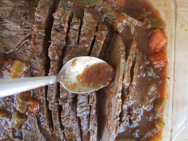 Spooning gravy over sliced brisket.