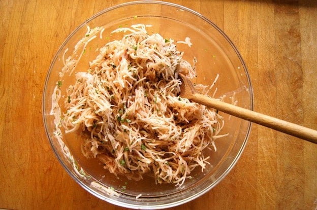 Stirring seasonings into shredded potatoes.