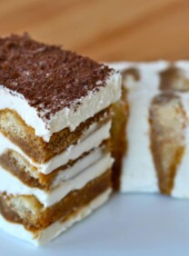 A slice of tiramisu cake with layers of coffee-soaked ladyfingers, creamy mascarpone cheese, and a dusting of cocoa powder