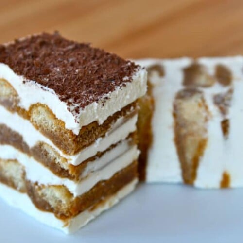 A slice of tiramisu cake with layers of coffee-soaked ladyfingers, creamy mascarpone cheese, and a dusting of cocoa powder