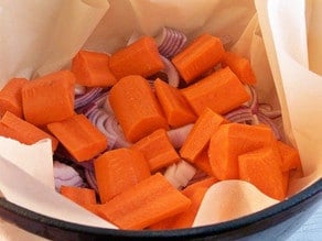 Diced carrots in a parchment lined Dutch oven.