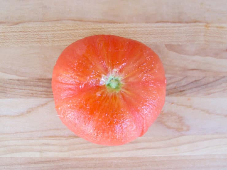Peeled tomato on cutting board.
