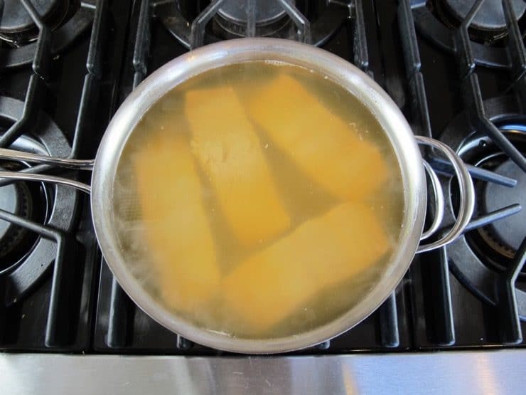 4 salmon fillets in a pot of Court Bouillon - Steaming hot, barely boiling, on stovetop.