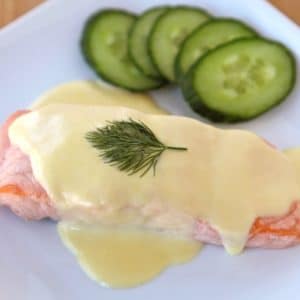 Salmon Mousseline on a white plate with sprig of dill and cucumber salad on the side.