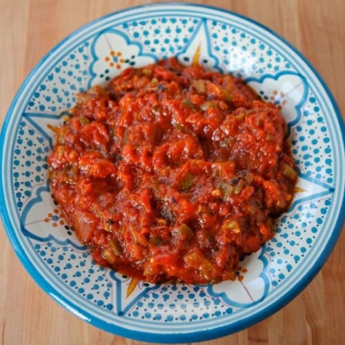 Horizontal shot of Moroccan Matbucha on circular blue patterned plate.