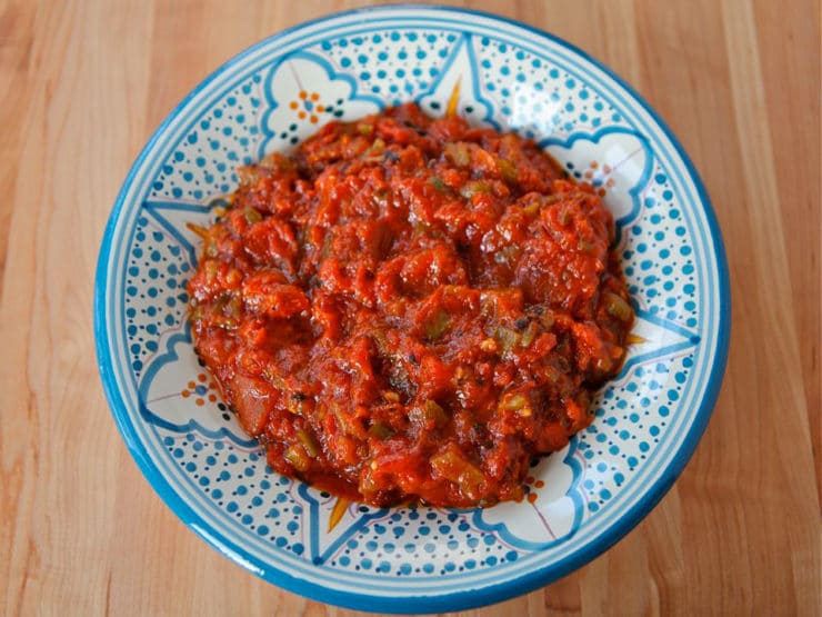 Horizontal shot of Moroccan Matbucha on circular blue patterned plate.