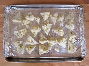 Cauliflower florets on a baking sheet sprinkled with salt and pepper.