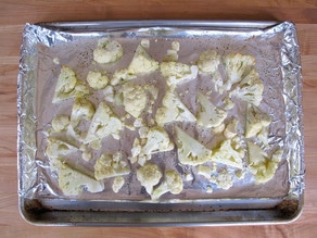 Half-roasted cauliflower florets on baking sheet.