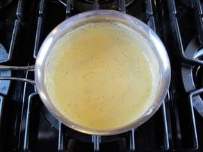 Melting cheese into milk in a saucepan.