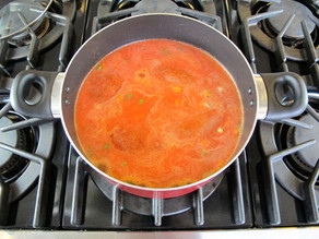 Chicken pieces added to stockpot of tomato juice.