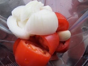 Tomatoes and onion in a blender jar.