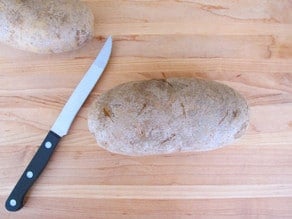 Baked potato on a cutting board.