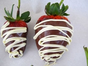 Chocolate drizzled on dipped strawberries.