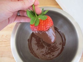Dipping a strawberry in chocolate.