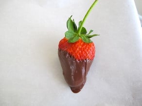 Chocolate dipped strawberry on parchment.