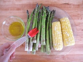 Brushing asparagus spears with oil.