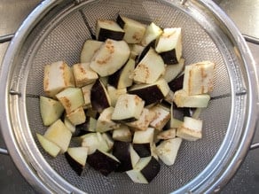 Cubed eggplant draining in a colander.