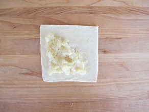 Mashed potato filling on puff pastry square.