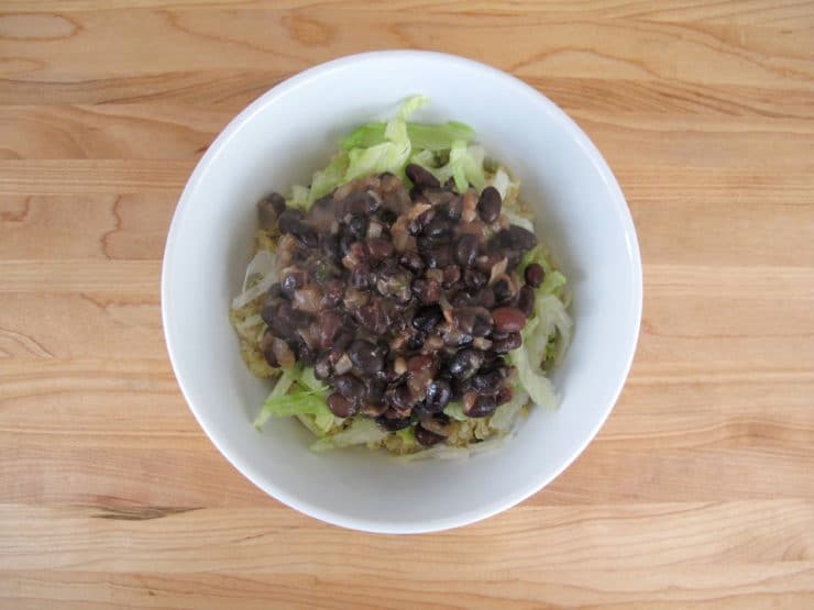 Black beans on top of lettuce and quinoa.