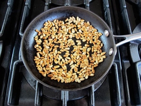 Dry toasting pine nuts in a skillet.