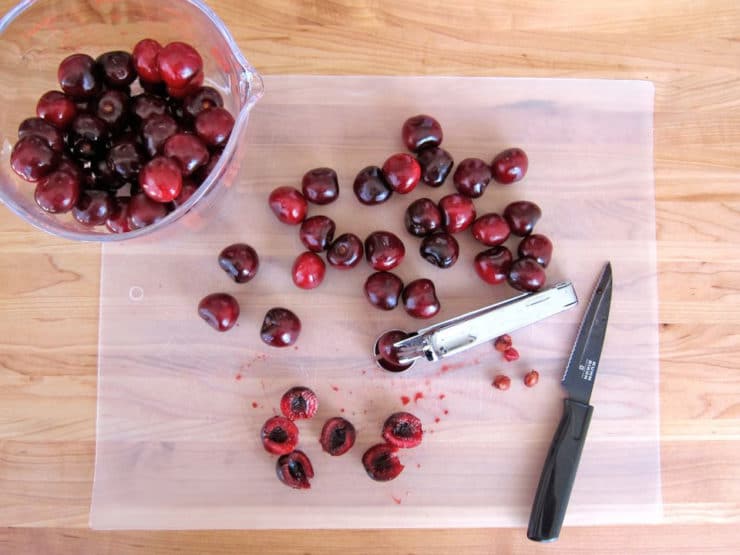 Pitting cherries on a cutting board.