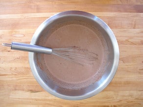 Whisking cocoa into whipping cream.