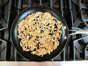 Dry toasting almonds in a skillet.