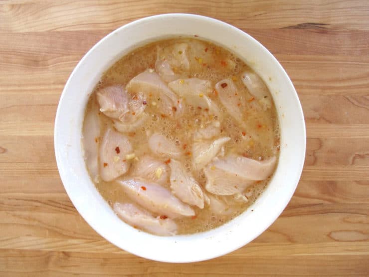 Chicken tenders marinating in a bowl.