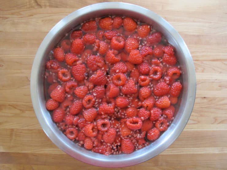 Boiling sugar water poured into a bowl of raspberries.