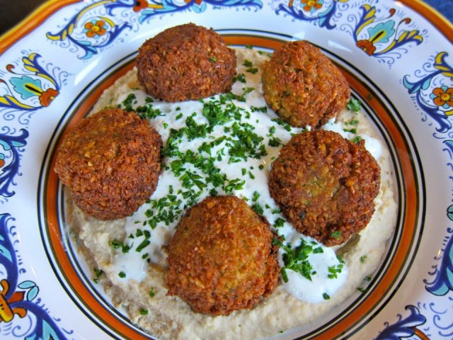 Plate with four falafel meatballs on hummus bowl
