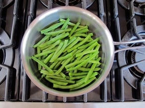 Steaming green beans in a saucepan.