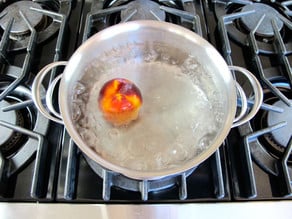 Simmering peach in boiling water.