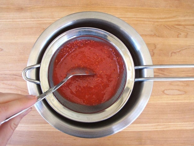 Straining raspberry puree.