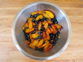 Sliced peaches macerating in a bowl.