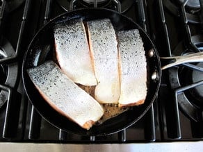 Searing salmon fillets in a skillet.