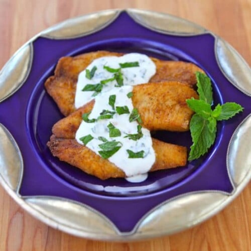 A plate of tilapia topped with a tangy Greek yogurt mint sauce