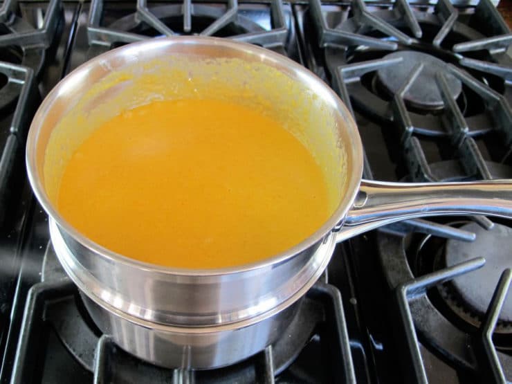 Beating egg into cheese sauce.