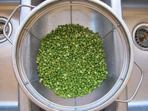 Rinsing split peas in a strainer.