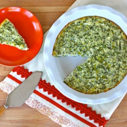 A plate with a crustless quiche featuring spinach, cheese, feta, and asparagus