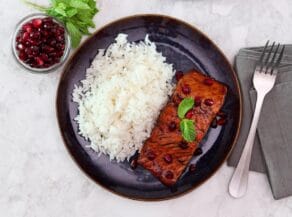 Overhead shot of a plate containing a fillet of pomegranate glazed salmon next to a serving of white rice.