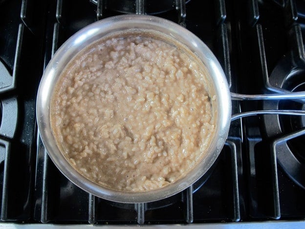 Cooked rice added to a saucepan of coconut milk.