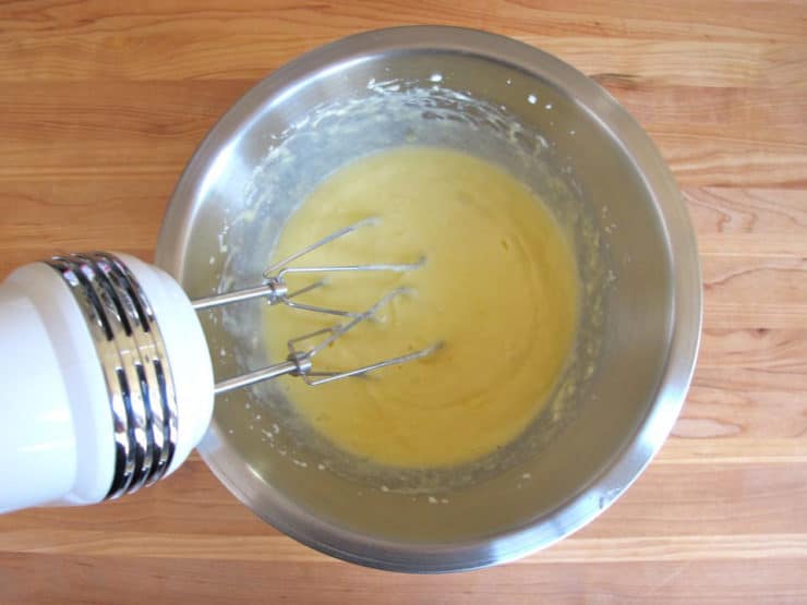 Eggs beaten into butter in a mixing bowl.