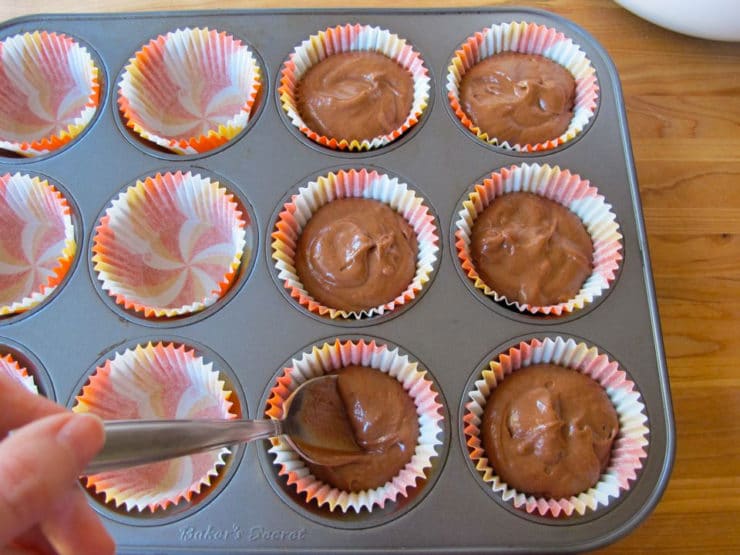 Filling muffin tins with chocolate batter.