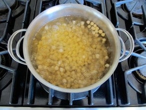 Boiling chickpeas in a large pot on stovetop for quick soaking.